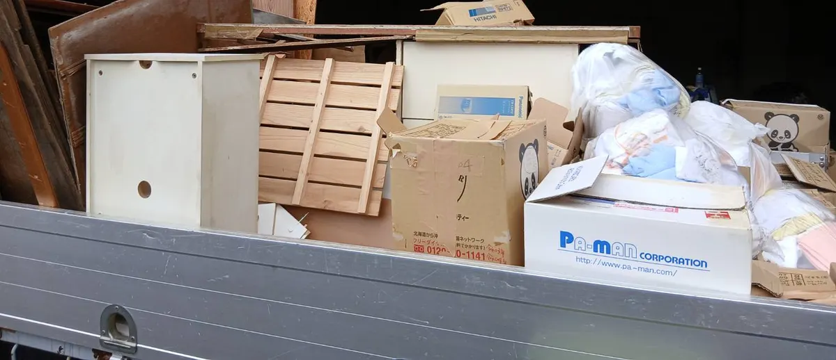 トラックの荷台に積んだ白い棚・すのこ・段ボール・衣類の入った袋